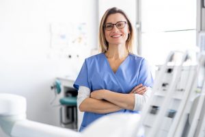 Smiling Dentist With Folded Hands in Dental Office