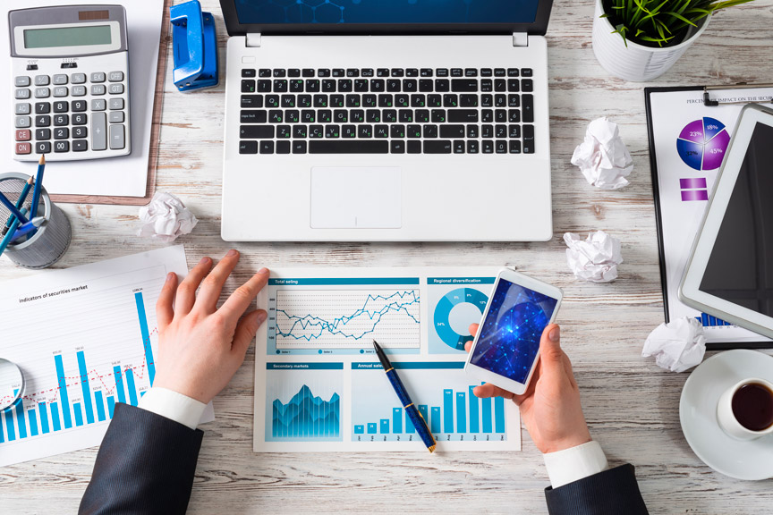 Person Analyzing Data By Seeing Smartphone And Laptop