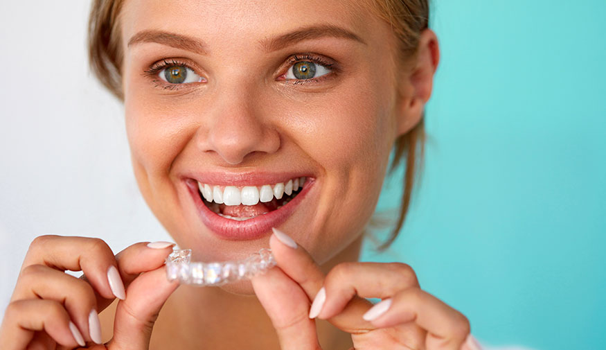 Smiling Woman Holding A Clear Aligner